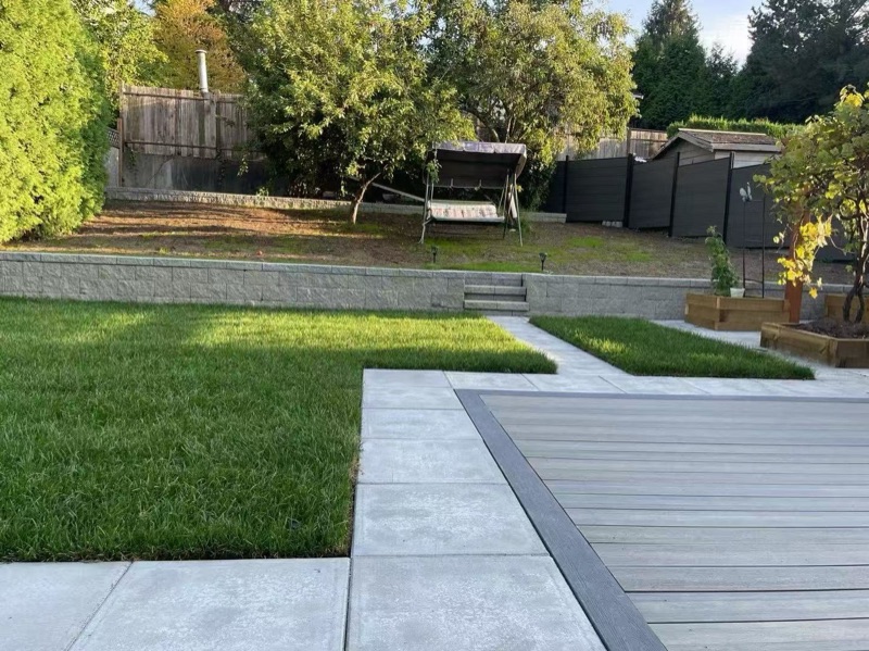 Backyard with composite deck, lawn, concrete borders, and raised planter boxes
