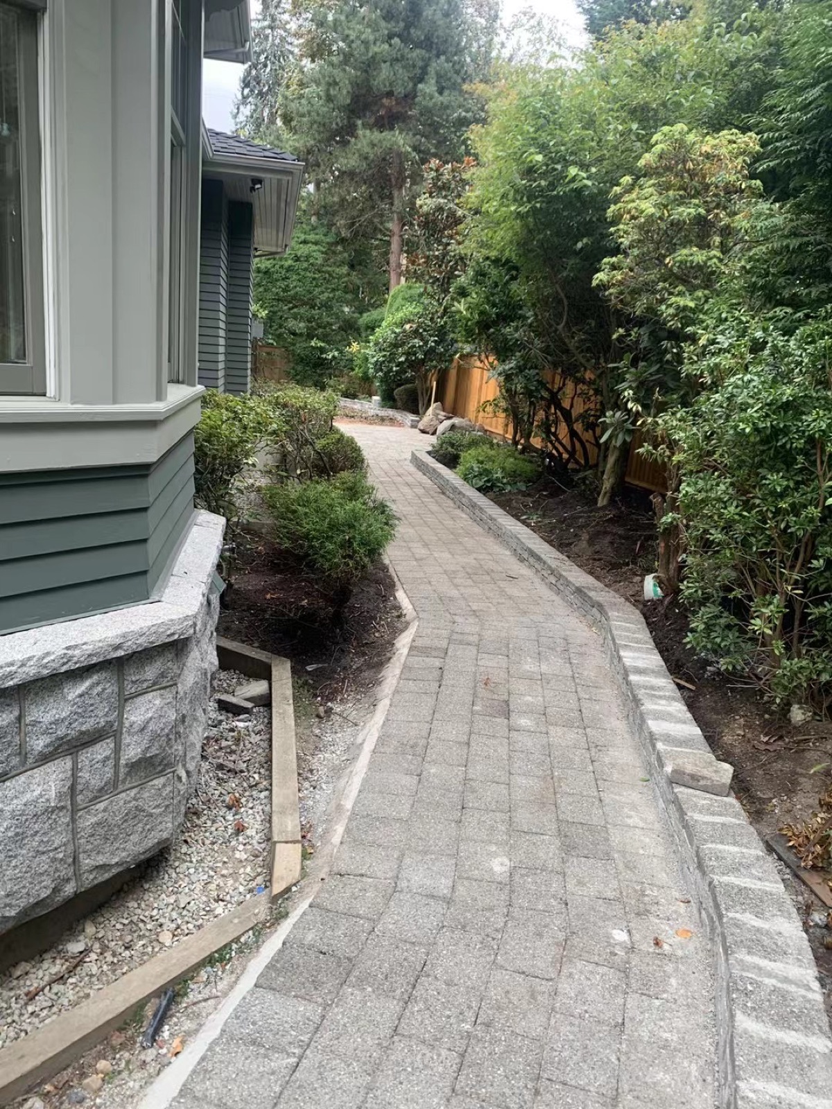 Brick paver walkway along house with landscaping